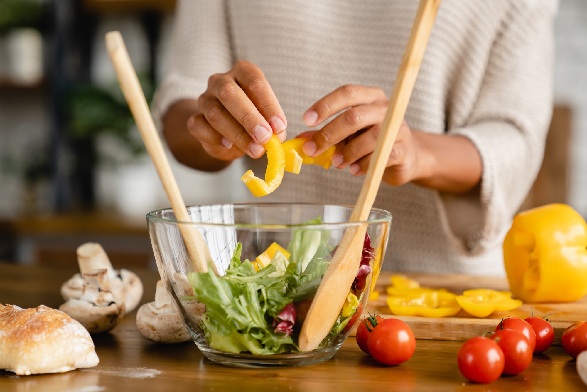 Woman`s hands making vegetable salad, cutting vegetables for vegan vegetarian food meal at kitchen.